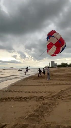 Parasailing and jet skis on a cloudy Pattaya morning