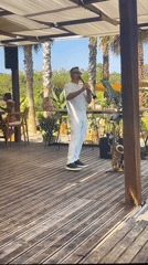 Musician performs clarinet on outdoor deck near palm trees