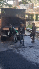 Road construction underway in Vashisht, India with workers spreading asphalt