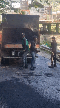 Road construction underway in Vashisht, India with workers spreading asphalt