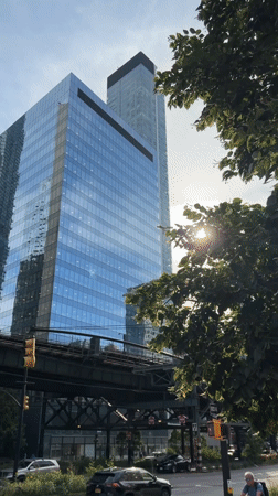 Elevated train cuts through a corridor of NYC skyscrapers
