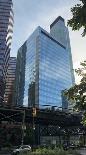 Elevated train cuts through a corridor of NYC skyscrapers