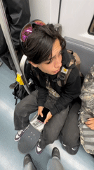 Young skateboarder rides subway with phone, purple sneakers noted