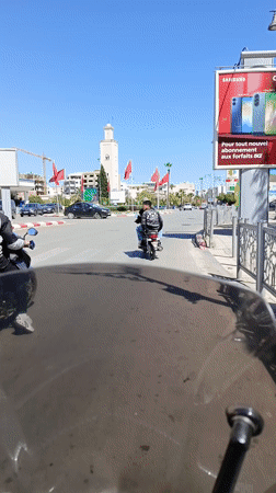 Street scene documented in Meknès featuring minaret and flags
