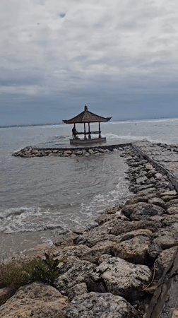 Early morning beach activity captured along Denpasar's rocky coastline