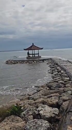 Early morning beach activity captured along Denpasar's rocky coastline