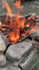 Forest camping site with handmade furniture and active fires documented