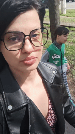 Woman takes street selfie as boy walks behind