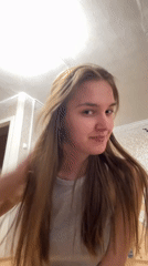 Woman adjusts hair, smiles indoors in Perm, Russia