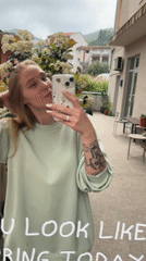 Woman records mirror selfie with yellow smiley shopping bag