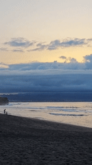 Surfers and onlookers at dusk on Ribeira Grande's dark sand beach