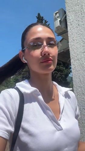 Woman in white shirt and sunglasses observed outdoors in Bar