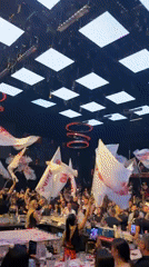 Aerial performer entertains nightclub crowds with colorful light display