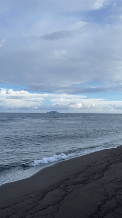 Morning at Dauin's black sand beach — boats, paddleboards, and ocean.