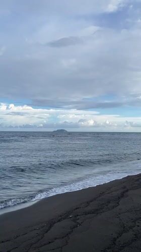 Morning at Dauin's black sand beach — boats, paddleboards, and ocean.