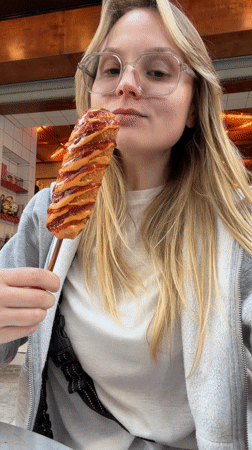 Woman enjoys corndog with condiments in Amman