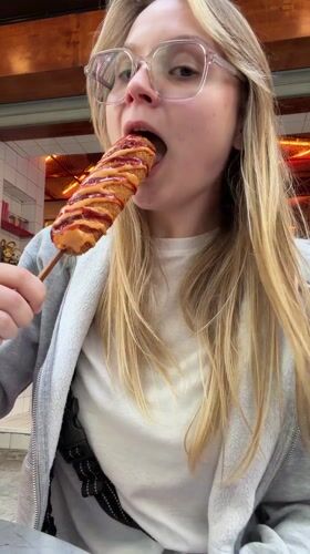 Woman enjoys corndog with condiments in Amman