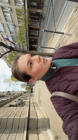 Woman walks past ornate buildings and flower gardens in Belgrade