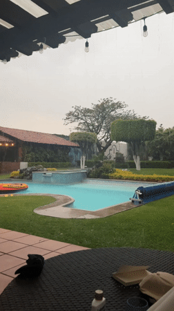 Person films backyard pool during nighttime rainfall