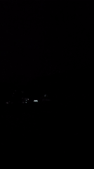 Distant lightning storm lights up a dark rural horizon