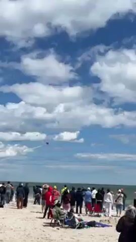 Here is a description of the video:

The video captures a fighter jet soaring through the sky, leaving a trail of white smoke behind it. The backdrop consists of a dynamic sky filled with fluffy white and grey clouds, set against a background of blue sky. The jet moves swiftly across the frame, providing a sense of motion and aerial prowess.
