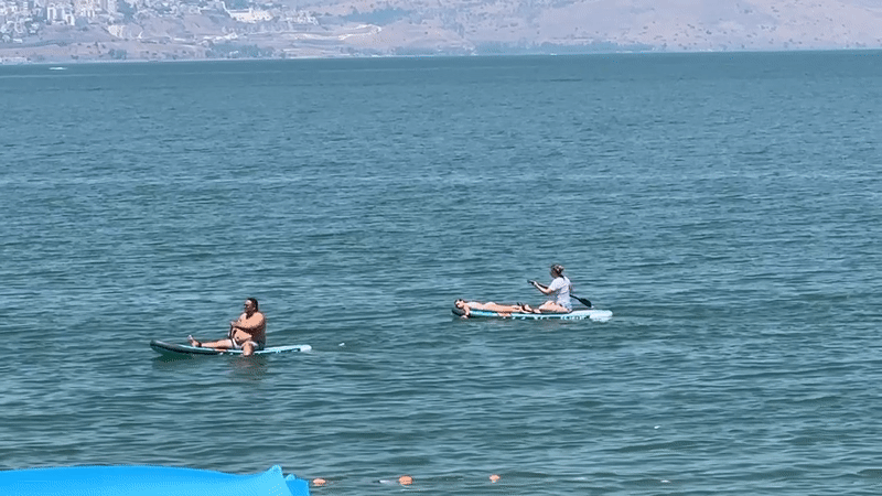 Paddleboarding on the Sea of Galilee, Tiberias shoreline behind