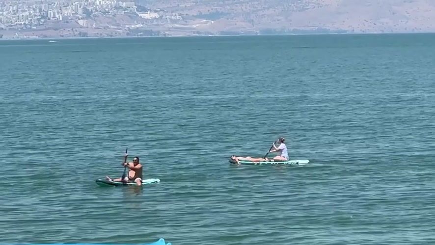 Paddleboarding on the Sea of Galilee, Tiberias shoreline behind