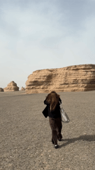 Woman walks through desert landscape near Dunhuang, China