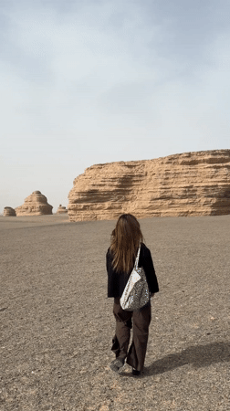 Woman walks through desert landscape near Dunhuang, China