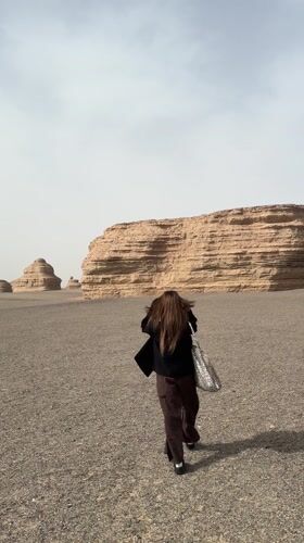 Woman walks through desert landscape near Dunhuang, China