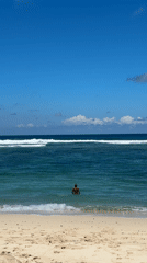 Person stands waist-deep in ocean waters off Kuta Selatan
