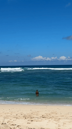 Person stands waist-deep in ocean waters off Kuta Selatan
