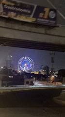 Illuminated Ferris wheel spotted under highway overpass in Puebla