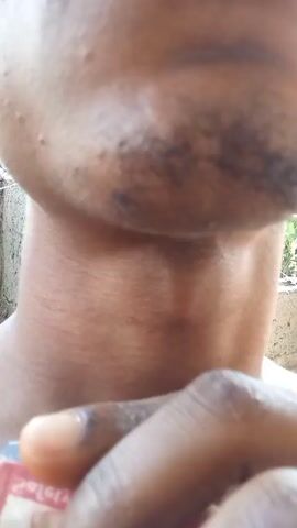 The video shows a close-up of a person's neck and chin. The person is holding a small, red and white package in their hand. The background is blurry and appears to be outdoors. The focus of the video is on the person's neck.
