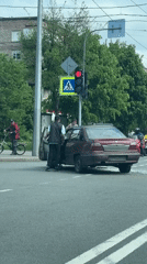 Car accident involving burgundy sedan blocks urban crosswalk