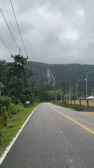 Winding rural road cuts through lush greenery in Ngao, Thailand