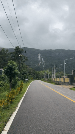 Winding rural road cuts through lush greenery in Ngao, Thailand