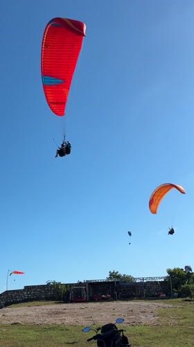 Paragliders launch from Indonesian coastal cliffs under clear skies
