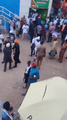 Large crowd gathers in plaza wearing casual, traditional attire