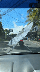 Motorcyclist carries oversized banner on Denpasar street