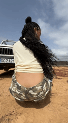 Woman crouches beside white Jeep in Tinajo, Spain