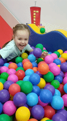 Children play at indoor party venue with ball pits