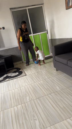 Mother and child play ball indoors in Kamaza home