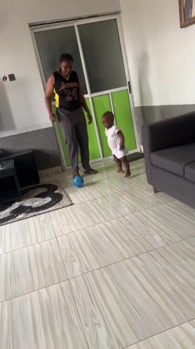 Mother and child play ball indoors in Kamaza home