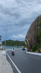 Traffic flows along scenic coastal road in Thailand