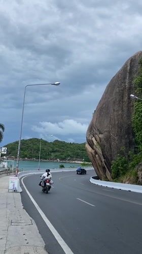 Traffic flows along scenic coastal road in Thailand