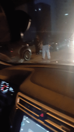 Evening street activity in Meknès with pedestrians and parked car