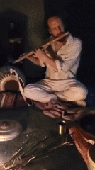 Flute player performs beside traditional cooking fire in Haini