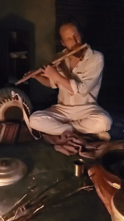Flute player performs beside traditional cooking fire in Haini
