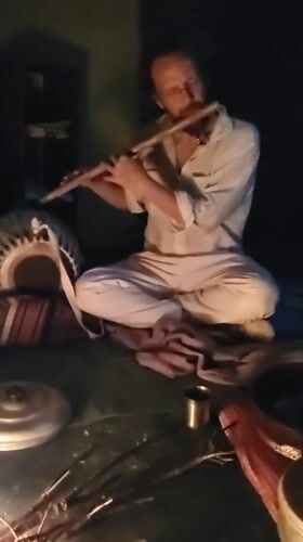 Flute player performs beside traditional cooking fire in Haini